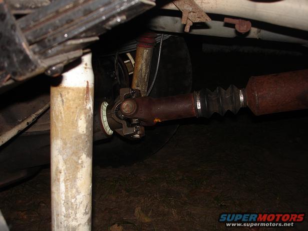 Underside view of a vehicle's driveshaft, U-joint, and part of the suspension system