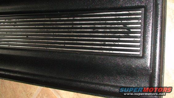 Close-up of a black textured panel with a section of horizontal silver stripes