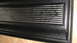 1979 Ford Bronco - This image shows a close-up of a black textured panel with a series of horizontal silver stripes.