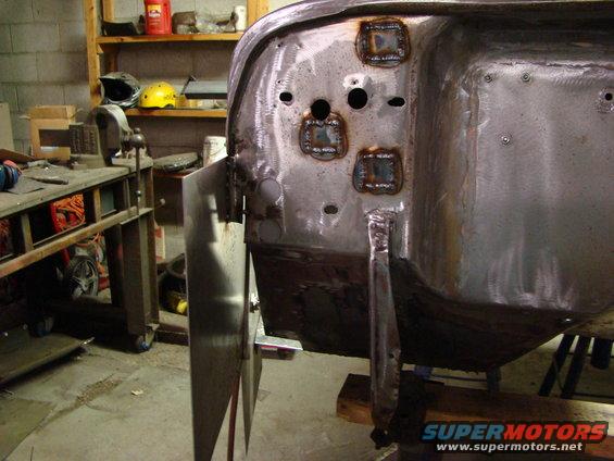 Welded patches on bare metal vehicle body panel in workshop