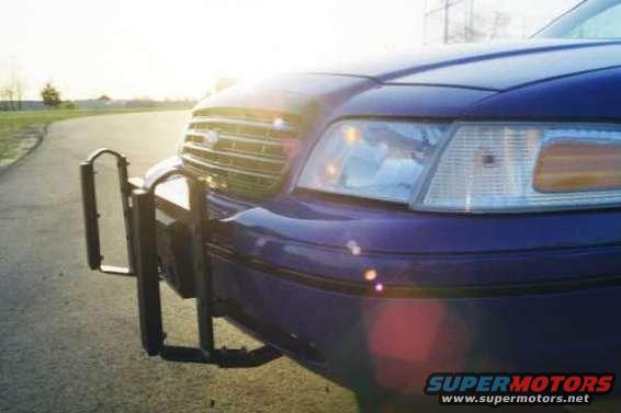 Front view of a dark blue police car with a push bar, showing the grille and headlight