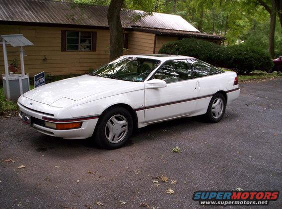 White coupe with pop-up headlights and a sunroof parked on asphalt