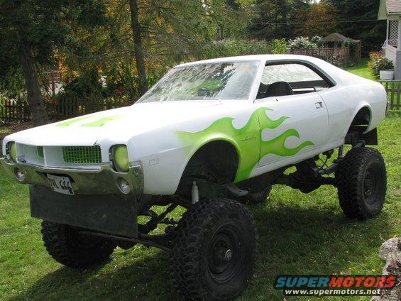 white muscle car on huge tires, green flame graphics on side and hood