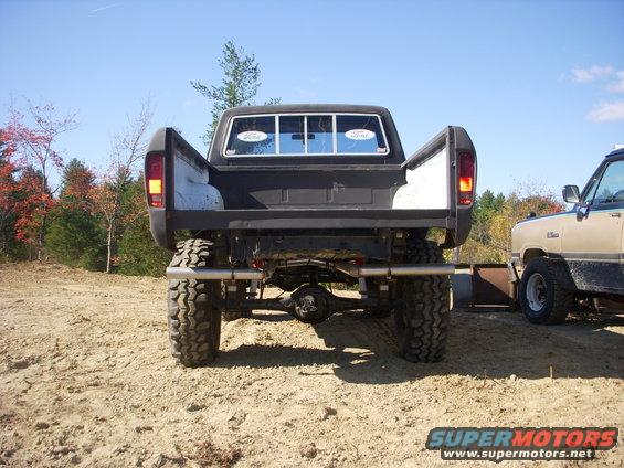 Rear view of a lifted black 1979 Ford F-150 with large tires, parked next to another pickup
