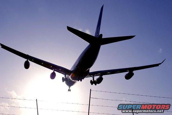 Airplane flying overhead against a blue sky, with landing gear down