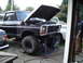 1979 Ford Bronco - Black Ford Bronco undergoing maintenance on jack stands, with a white truck visible in the background.