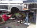 1979 Ford Bronco - Mechanic works on the front suspension of a 1979 Ford Bronco, which is raised on jack stands.