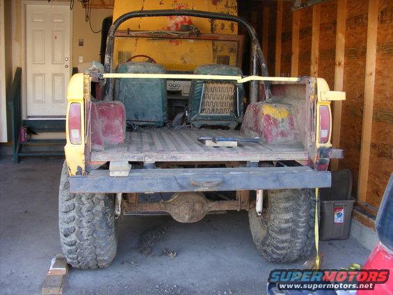 Rear view of a yellow 1974 Ford Bronco with red accents and large tires
