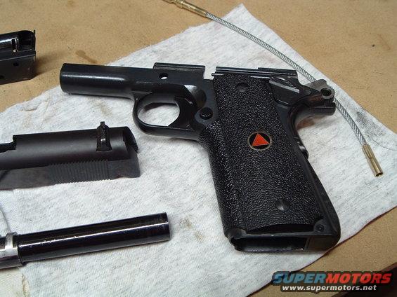 Disassembled handgun with frame, slide, and barrel laid out on a cloth