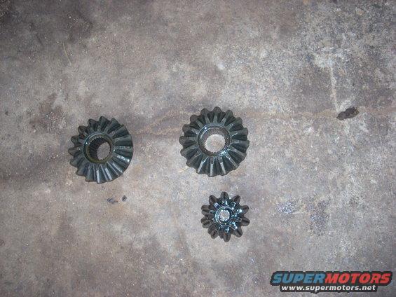 Three metal differential gears on a concrete surface