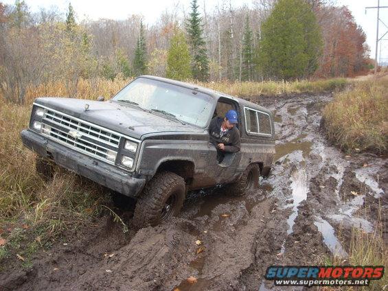 Dark gray 1988 Chevrolet Blazer stuck in mud, driver's side front tire deep in mire
