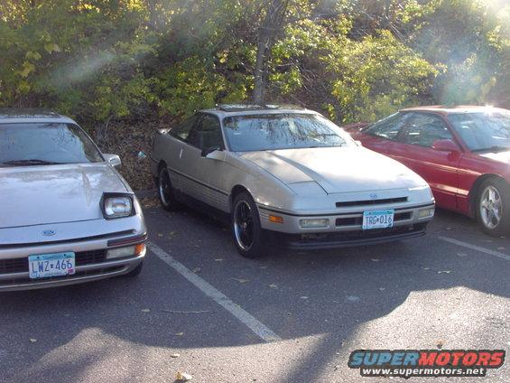 Silver 1991 Ford Probe coupe parked, front 3/4 view, with a red car to the right and a silver car to the left