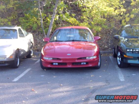 Red coupe front view, parked in a lot