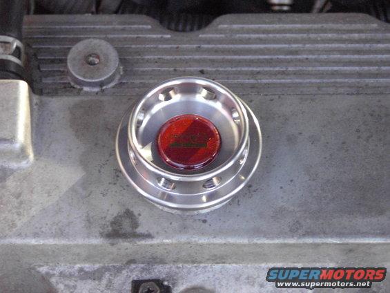 Close-up of engine oil cap with red insert and visible text