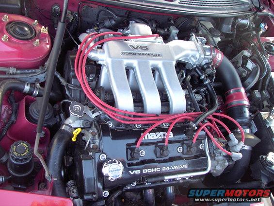 Engine bay shot showing a V6 DOHC 24-valve Mazda engine with red spark plug wires