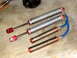 1996 Ford Bronco - Four shock absorbers, two with blue hoses, and a differential are laid out on a concrete surface.