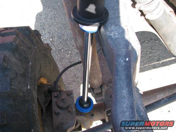 close-up of a shock absorber with blue bushings mounted to suspension components