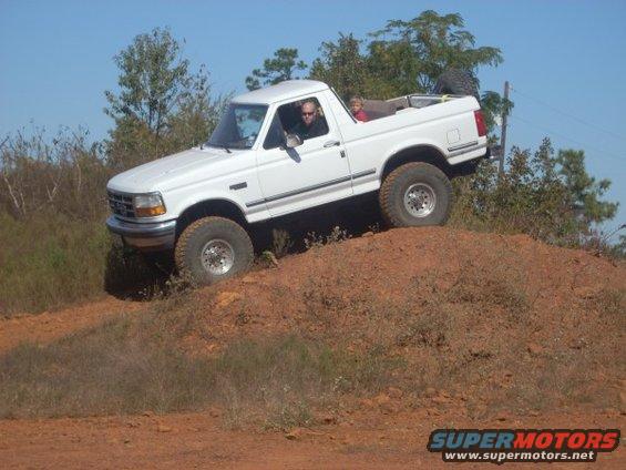 1992 Ford Bronco climbing a dirt hill with two people inside