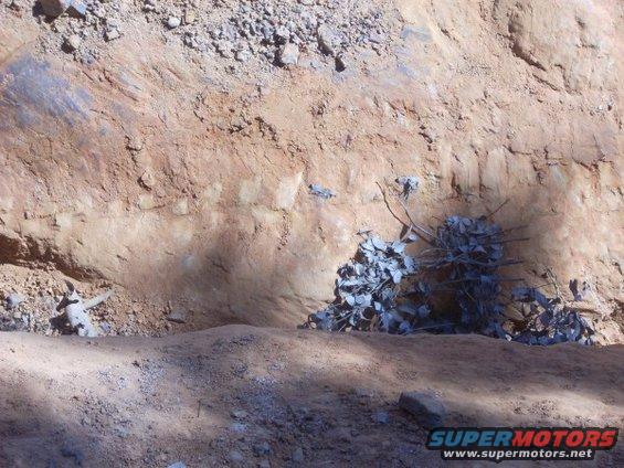 Construction site showing dirt embankment, rebar, and debris