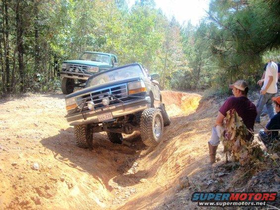 Blue 1992 Ford Bronco navigating a steep dirt trail with another truck behind it