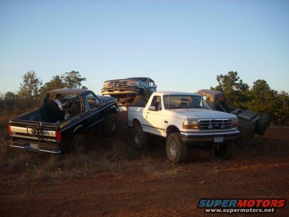 White 1992 Ford Bronco front 3/4 view off-roading with other vehicles