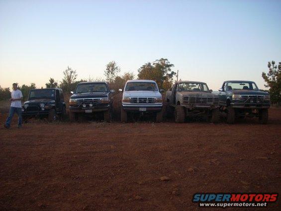 Jeep, two Ford Broncos, and two Ford F-Series trucks parked in dirt