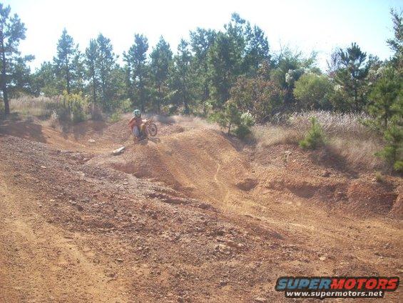 Dirt bike rider on a sandy hill with trees in the background