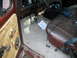 1979 Ford F-150 - The interior of a truck shows a worn brown seat, a makeshift wood door panel, and a cluttered floor with papers.
