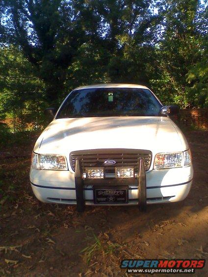 White Ford Crown Victoria with push bar and "SHERIFFS" plate. Model year appears to be late 90s