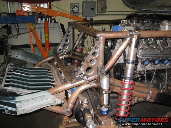 custom tube chassis with engine and suspension components, orange engine hoist in background