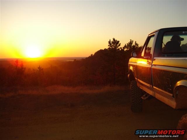 Pickup truck at sunset, side view. The truck is gold and brown with large tires