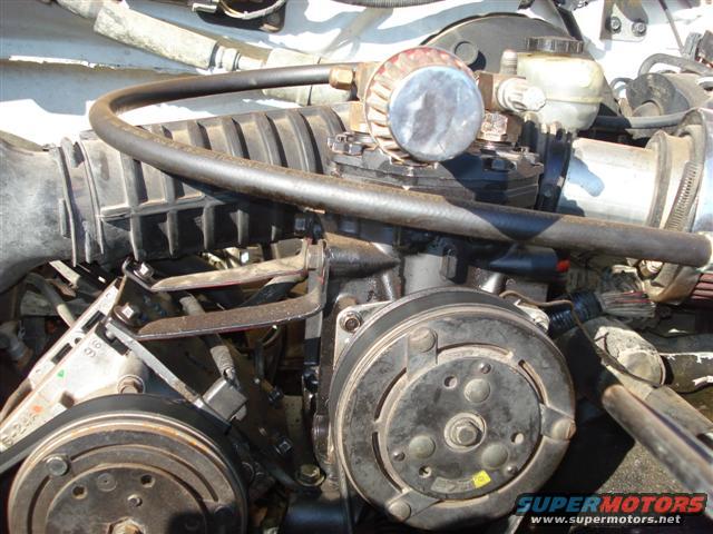 Engine compartment with air intake hose, compressor, and other engine parts visible