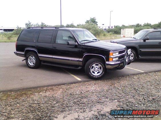 Black Chevrolet Suburban parked on asphalt with a second dark SUV behind it