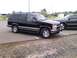 1998 Chevrolet Tahoe - A black Chevrolet Suburban is parked in a lot, with another vehicle visible behind it.