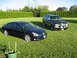 1998 Chevrolet Tahoe - A dark sedan and a black SUV are parked on a grassy lawn with manicured hedges in the background.