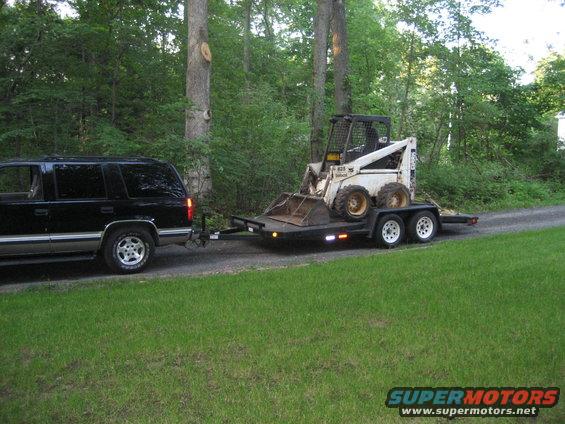 1998 Chevrolet Tahoe side view towing a trailer with skid steer loader