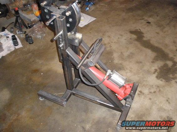 Homemade tube bender with a red hydraulic ram and metal frame