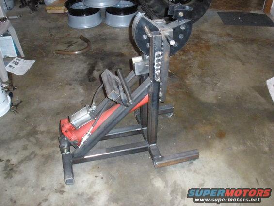 Homemade tire changer with red and silver components on a metal frame