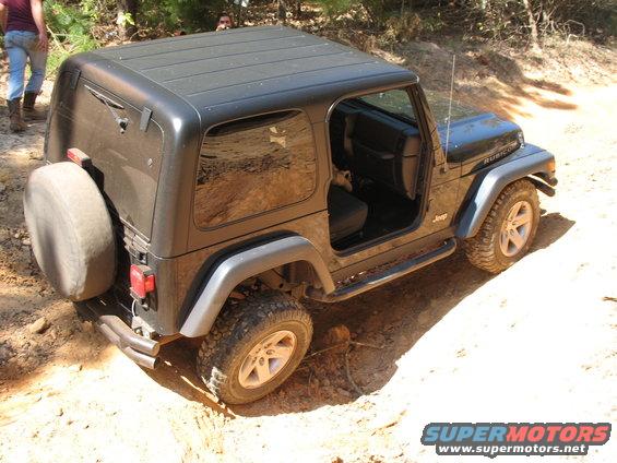 Overhead view of a black Jeep Wrangler Rubicon with spare tire on a dirt trail