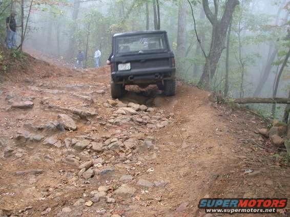 Black SUV on a rocky trail, rear view. Foggy forest background