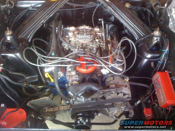 Engine bay showing V8 engine, carburetor, distributor, alternator, and red ignition box