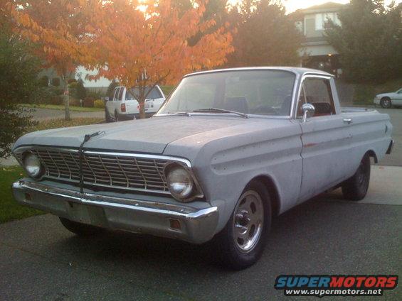Gray Ford Falcon Ranchero pickup truck, primer finish, parked in driveway. Autumn trees in background