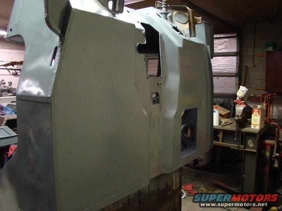 Gray vehicle body undergoing restoration, showing panel work and cutouts