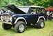 1972 Ford Bronco - A dark blue 1972 Ford Bronco is parked on grass with its hood open, revealing the engine bay.