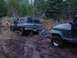 1988 Chevrolet Blazer - Two off-road vehicles are stuck in a muddy trail, with one vehicle attempting to pull the other.
