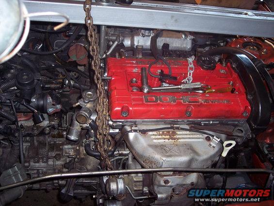 engine with red DOHC 16-VALVE cover, chain hoist attached, tools on top