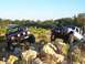 1998 Jeep Cherokee - Two Jeep SUVs navigate a rocky obstacle course under a clear blue sky.
