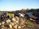 1998 Jeep Cherokee - Three Jeep SUVs navigate a challenging off-road course with rocky obstacles and sparse vegetation under a clear blue sky.