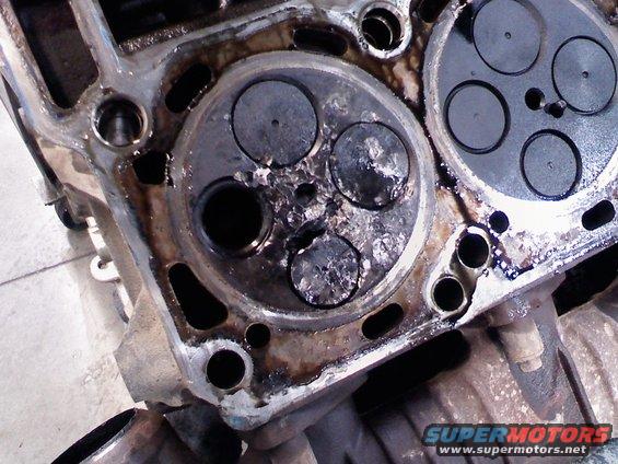 Close-up of a damaged engine cylinder head with burnt valves and carbon buildup