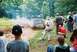 1972 Ford Bronco - A group of people watch an off-road vehicle navigate a muddy track.